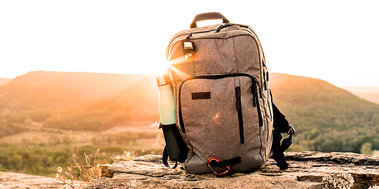 A camping bag with a water bottle, placed on a rock, with a mountain in the background. A camping bag with a water bottle, placed on a rock, with a mountain in the background.
