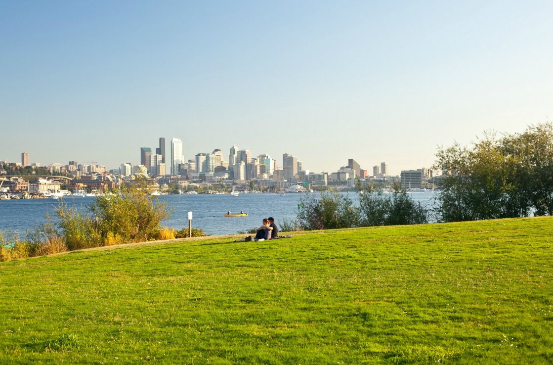 A couple sitting on the grass and looking at the river, in a park in Seattle. A couple sitting on the grass and looking at the river, in a park in Seattle.