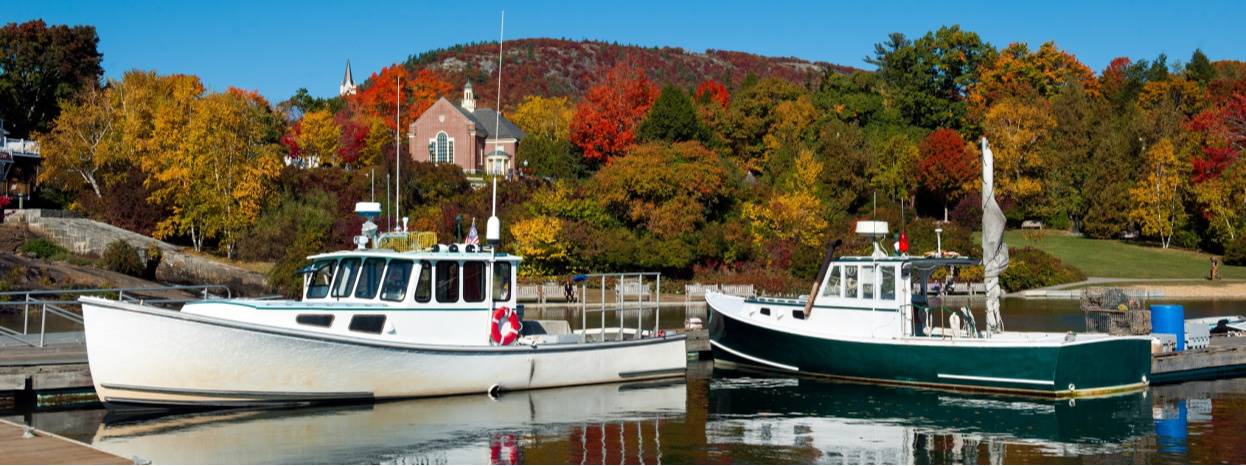 Two boats on a lake, fall-coloured trees in the background.