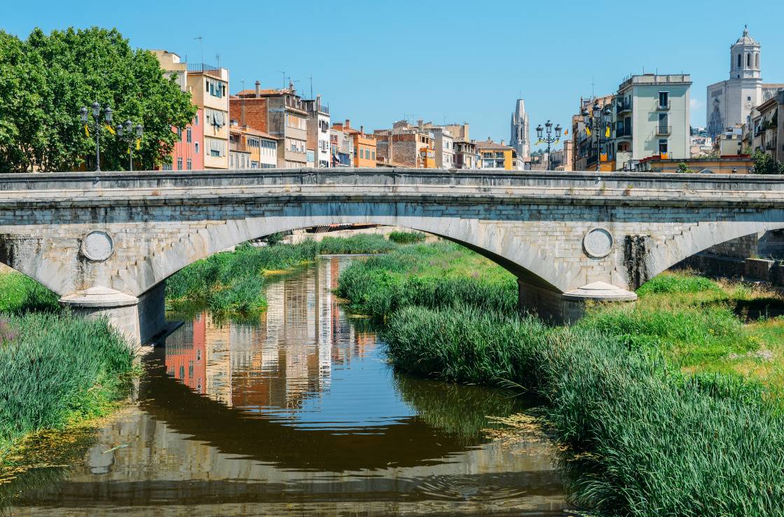 A stone bridge over the Onyar River, Girona in the bakcground. A stone bridge over the Onyar River, Girona in the bakcground.