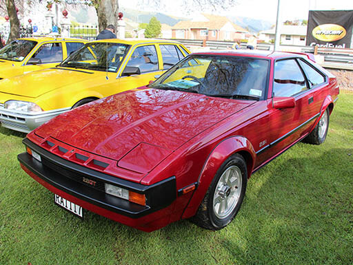 Red 1983 Toyota Supra A60 MkII 2800GT on display outdoors on a grassy field