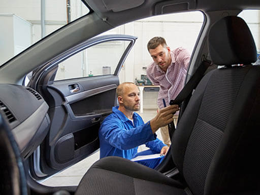 Two men looking at a car's seat belt