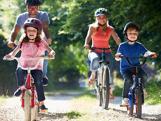 Young couple and two kids ride bikes on sunny day. Young couple and two kids ride bikes on sunny day.