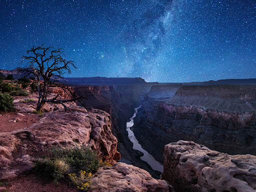 A magnificent starry sky overlooks the mountains surrounding the Colorado River at the Grand Canyon night