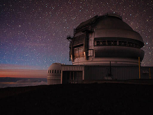 The starry nighttime sky shines over the star observatory at Mauna Key in Hawaii