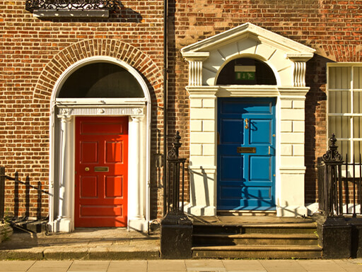 Gorgeous colorful red and blue doors on brown brick homes in Merrion Square on a sunny afternoon in Dublin, Ireland. Gorgeous colorful red and blue doors on brown brick homes in Merrion Square on a sunny afternoon in Dublin, Ireland.