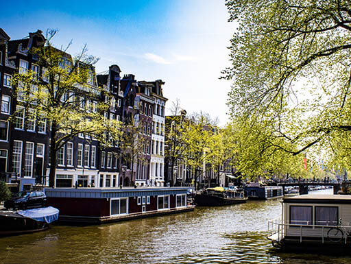 Glittering canal on a sunny spring day dotted with houseboats in Jordaan, Amsterdam Glittering canal on a sunny spring day dotted with houseboats in Jordaan, Amsterdam