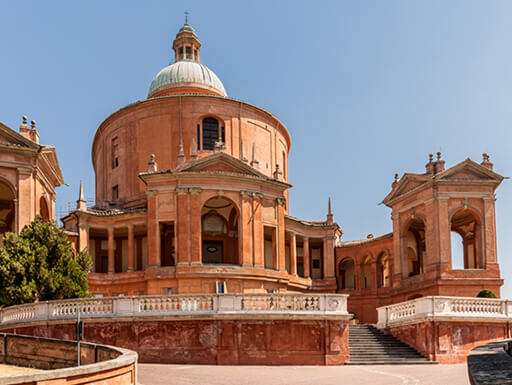 The Sanctuary of the Madonna di San Luca is a beautiful stone building sitting under the bright sun in Bologna, Italy.