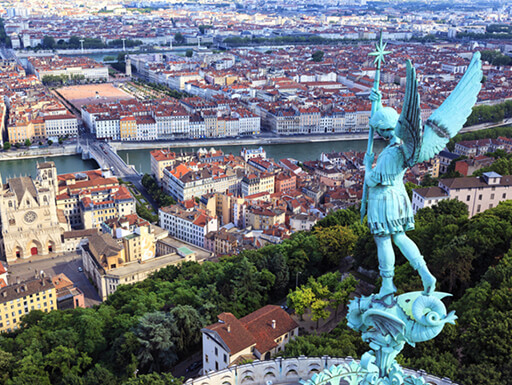 Daytime view of the city of Lyon from the top of the Notre Dame de Fourviere, topped with a bronze statue under clouds on an afternoon in France. Daytime view of the city of Lyon from the top of the Notre Dame de Fourviere, topped with a bronze statue under clouds on an afternoon in France.