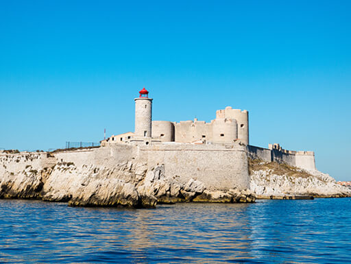 The former island prison of Chateau d’If near Marseille, France is an imposing stone fortress surrounded by clear water and a bright blue sky. The former island prison of Chateau d’If near Marseille, France is an imposing stone fortress surrounded by clear water and a bright blue sky.