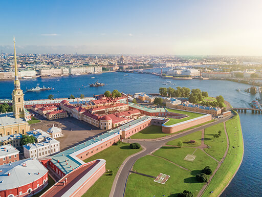 A bird’s eye view of Peter and Paul Fortress in St. Petersburg shows the colorful buildings and walls, surrounded by pristine landscaping, right on the edge of the water on a sunny day in Russia. A bird’s eye view of Peter and Paul Fortress in St. Petersburg shows the colorful buildings and walls, surrounded by pristine landscaping, right on the edge of the water on a sunny day in Russia.