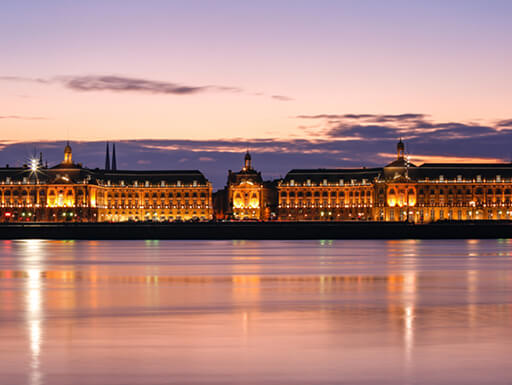 View looking across the Garonne river in Bordeaux to Place de la Bourse at sunset in France. View looking across the Garonne river in Bordeaux to Place de la Bourse at sunset in France.