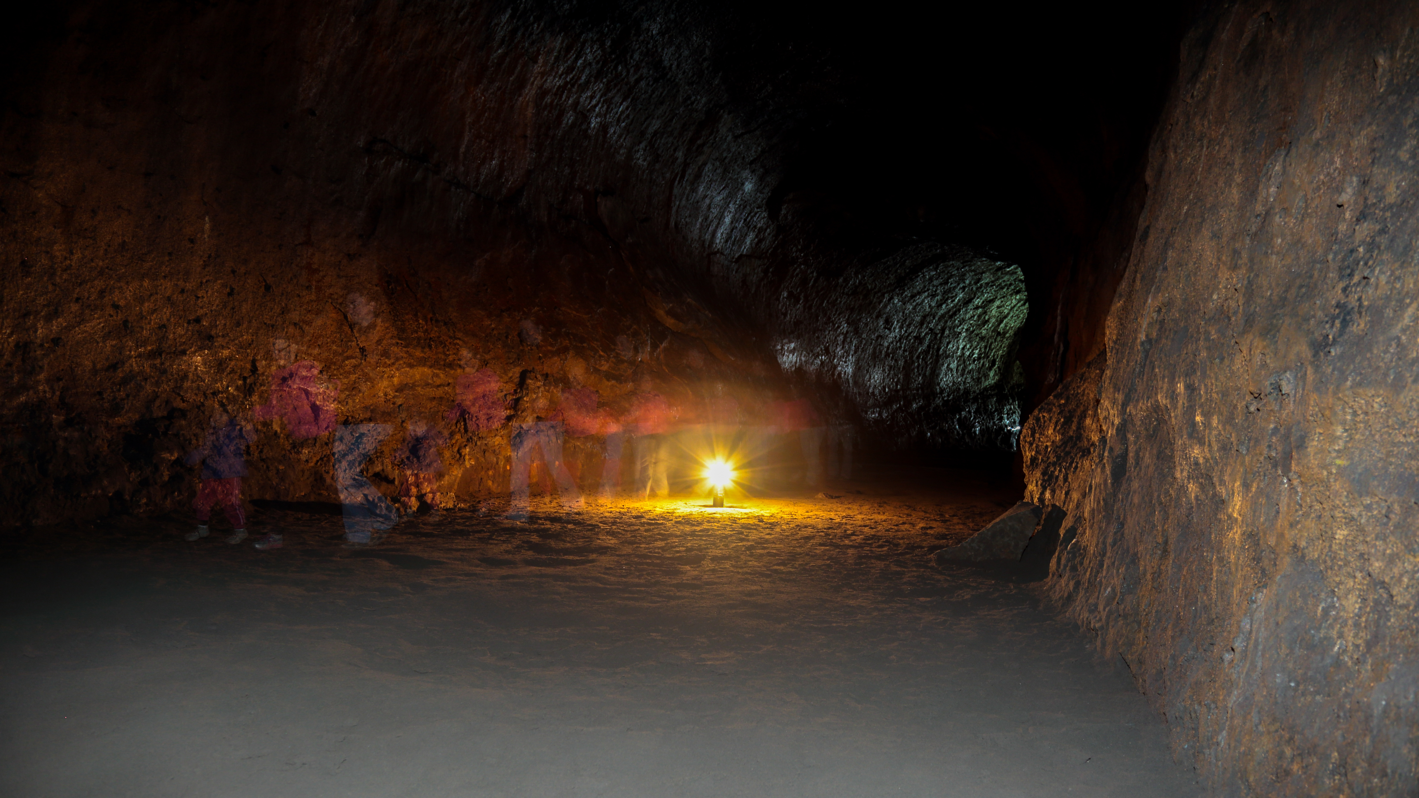 Ghosts walking inside Lava River Cave, Bend, Oregon. Long exposure photo of people passing by inside a lava tube illuminated by lantern light lava-river-cave
