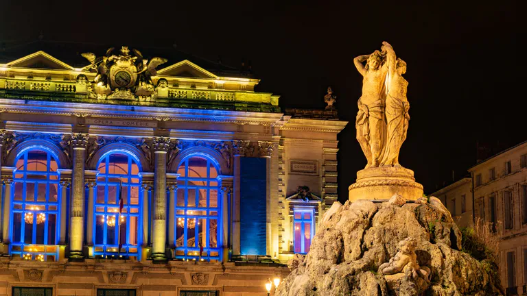 shot-of-beautiful-building-at-night-in-park-with-statue-in-foreground