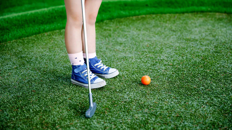 child playing mini golf