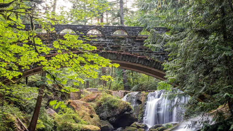 stone-bridge-over-river-and-waterfall-in-forest